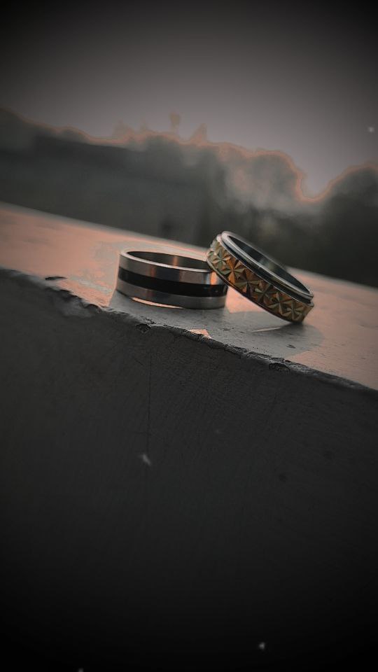 a pair of gold rings on a wooden surface